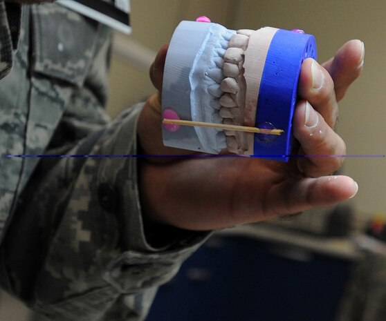 Technical Sergeant Joshuwa Steel holds together a mold of a patients mouth at the Dental Lab Sept. 22 at Joint Base Charleston-Air Base.  Wooden sticks are glued to the mold to hold it in place. Steel is a Dental Lab technician with the 628th Medical Group. (U.S. Air Force photo/Airman 1st Class Ashlee Galloway)