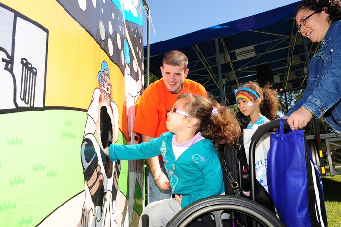 Tiana Lopez throws a baseball through the baseball toss game, while her sister Gaby and her mother Carolina watch at the Child Find/Exceptional Family Member Program Extravaganza ‘Special Needs Fair’ Oct. 1  at Marrington Plantation, Joint Base Charleston-Weapons Station.The fair is designed to help families with children who have special needs by providing entertainment while  keeping them aware of the resources available on and off base. The extravaganza  featured fun, food, games, prizes and music provided by more than 20 local resources agencies.  Tiana is the daughter of Carolina and Tech. Sgt. Jose Lopez recently left for a remote tour in Korea, was assigned to 437th Maintenance Squadron.  (U.S. Air Force photo/Tech. Sgt Chrissy Best) 

