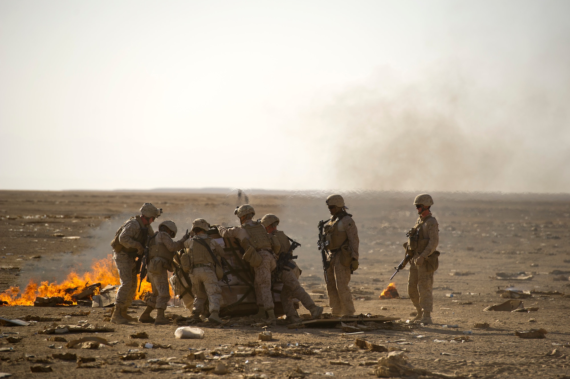 U.S. Marines deployed to Forward Operating Base Edinburgh roll over a bundle of food rations that was recently airdropped by A U.S. Air Force C-130 Hercules on Oct 3, 2011.  The supplies are loaded on trucks for transport back to the FOB and the parachutes and other packing material are collected and burned on site to reduce the debris left on the drop zone. Aerial delivery of food and water allows Marines to get some critical supplies without having to rely on risky ground convoys.   (U.S. Air Force Photo/Master Sgt. Jeffrey Allen)