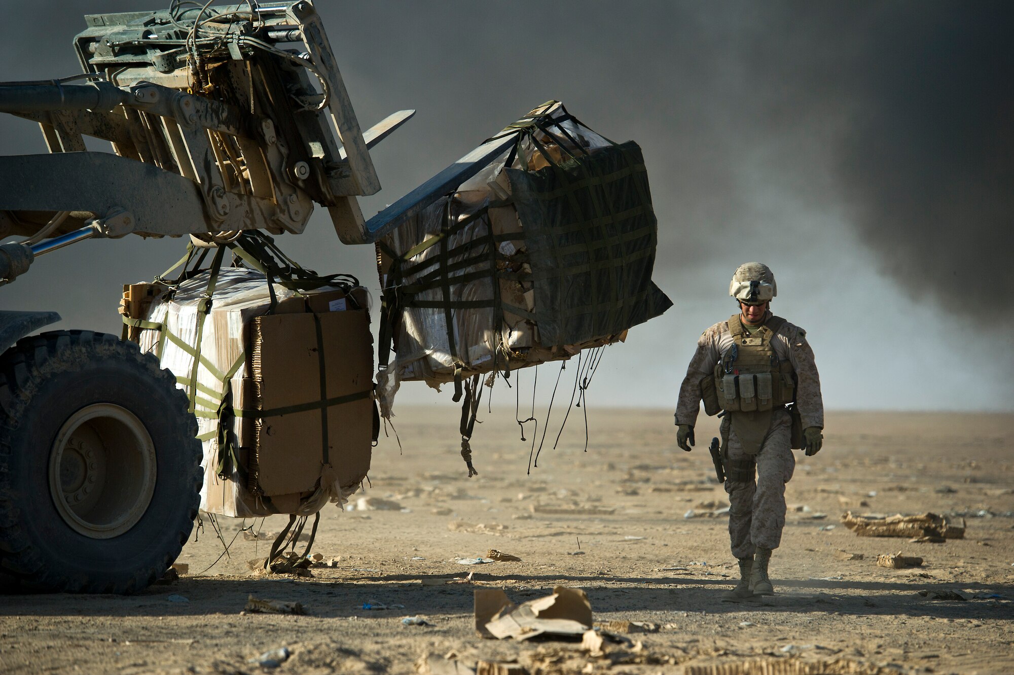 A U.S. Marine helps collect bundles of food rations that were airdropped to Forward Operating Base Edinburgh, the logistics hub for Northern Helmand Province, on Oct. 3, 2011. The parachutes and other packing material are collected and burned on site to reduce the debris left on the drop zone. Aerial delivery of food and water allows Marines to get some critical supplies without having to rely on risky ground convoys.   (U.S. Air Force Photo/Master Sgt. Jeffrey Allen)