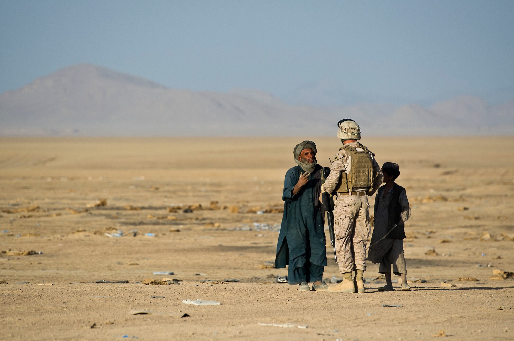 U.S. Marine Sgt. Davies hands out food and water as he asks local Afghans to leave Forward Operating Base Edinburgh's drop zone minutes before a schedule air drop of food on Oct 3, 2011. For safety reasons, Marines keep the DZ clear of local Afghans who often gather around the drop zone looking for material left behind. (U.S. Air Force Photo/Master Sgt. Jeffrey Allen)