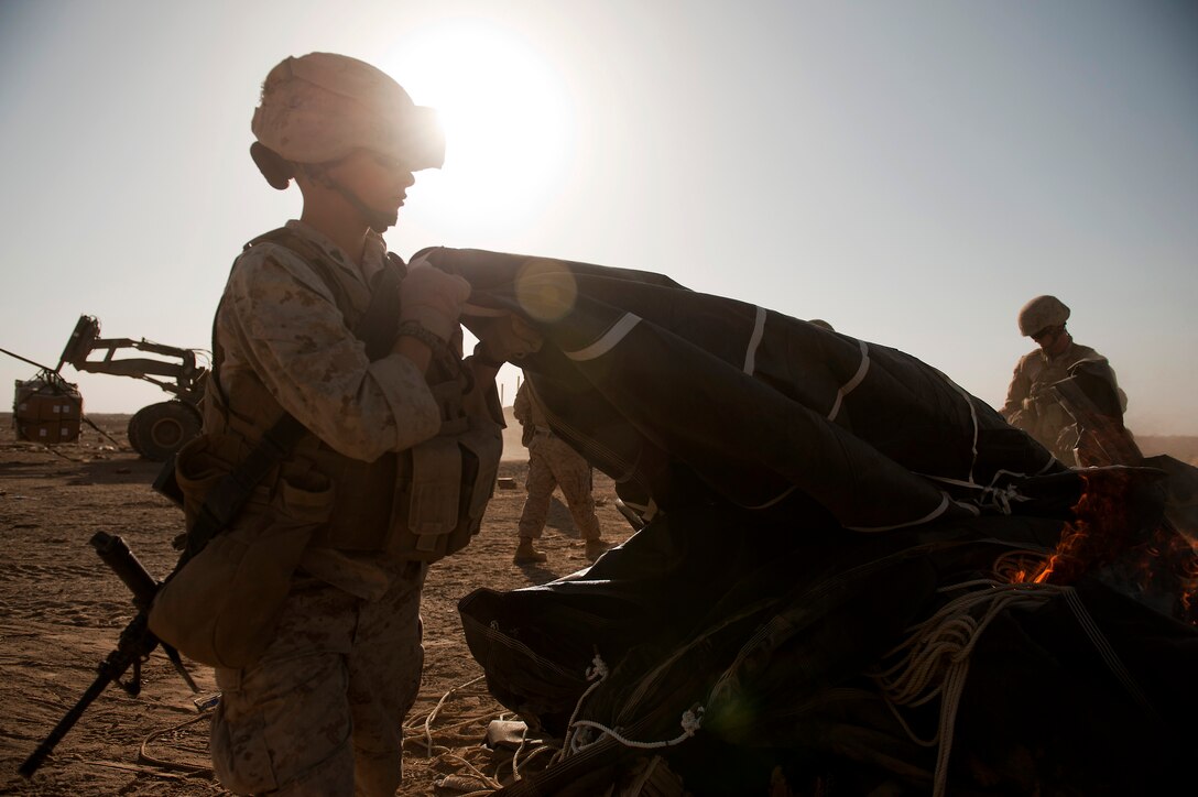 U.S. Marine Cpl. Alexandra Melnick sets fire to a parachute used during an airdrop on Forward Operating Base Edinburgh's drop zone in Helmand province, Afghanistan, Oct 3, 2011. Melnick is assigned to 2nd Battalion, 4th Marines of the 5th Marine Regiment. The troops burn the parachutes and other packing materials at the on-site to reduce the debris left on the drop zone.