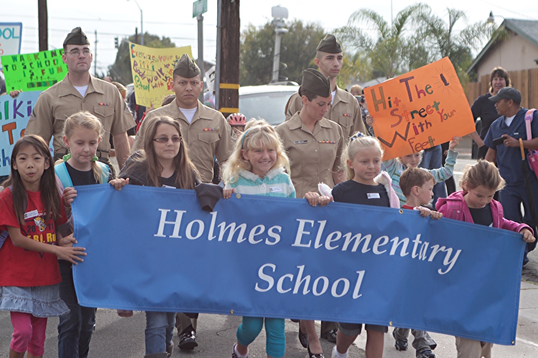Marines with Headquarters and Service Battalion walk with students from Holmes Elementary School for the National Walk to School Day Oct. 5. The National Walk to School Day is meant to encourage a safer community environment for students walking to school and a healthier lifestyle. Students carried signs encouraging walking to school and an assembly was held immediately following to thank participants for their dedication to the cause.