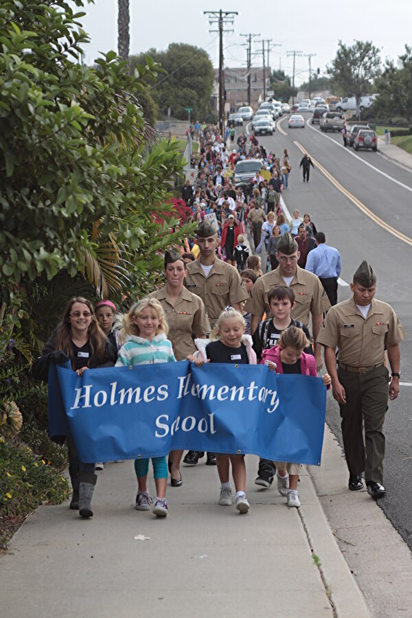 Marines with Headquarters and Service Battalion walk with students from Holmes Elementary School for the National Walk to School Day Oct. 5. The National Walk to School Day is meant to encourage a safer community environment for students walking to school and a healthier lifestyle. Students carried signs encouraging walking to school and an assembly was held immediately following to thank participants for their dedication to the cause.