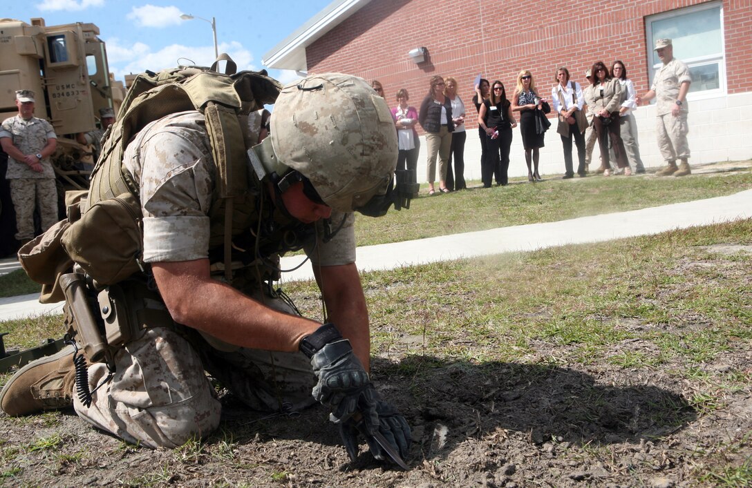 Sgt. Samuel A. Beltram, an explosive ordnance disposal technician with EOD Company, 8th Engineer Support Battalion, 2nd Marine Logistics Group, digs out an improvised explosive device as a demonstration during the 2nd MLG Senior Leaders’ Spouse Orientation tour aboard Camp Lejeune, N.C., Oct. 6, 2011. The day included a period of military education, where spouses were given a brief description of the different sections throughout the 2nd MLG, from the commanding general and sergeant major to the regiments and companies.  (U.S. Marine Corps photo by Cpl. Bruno J. Bego)