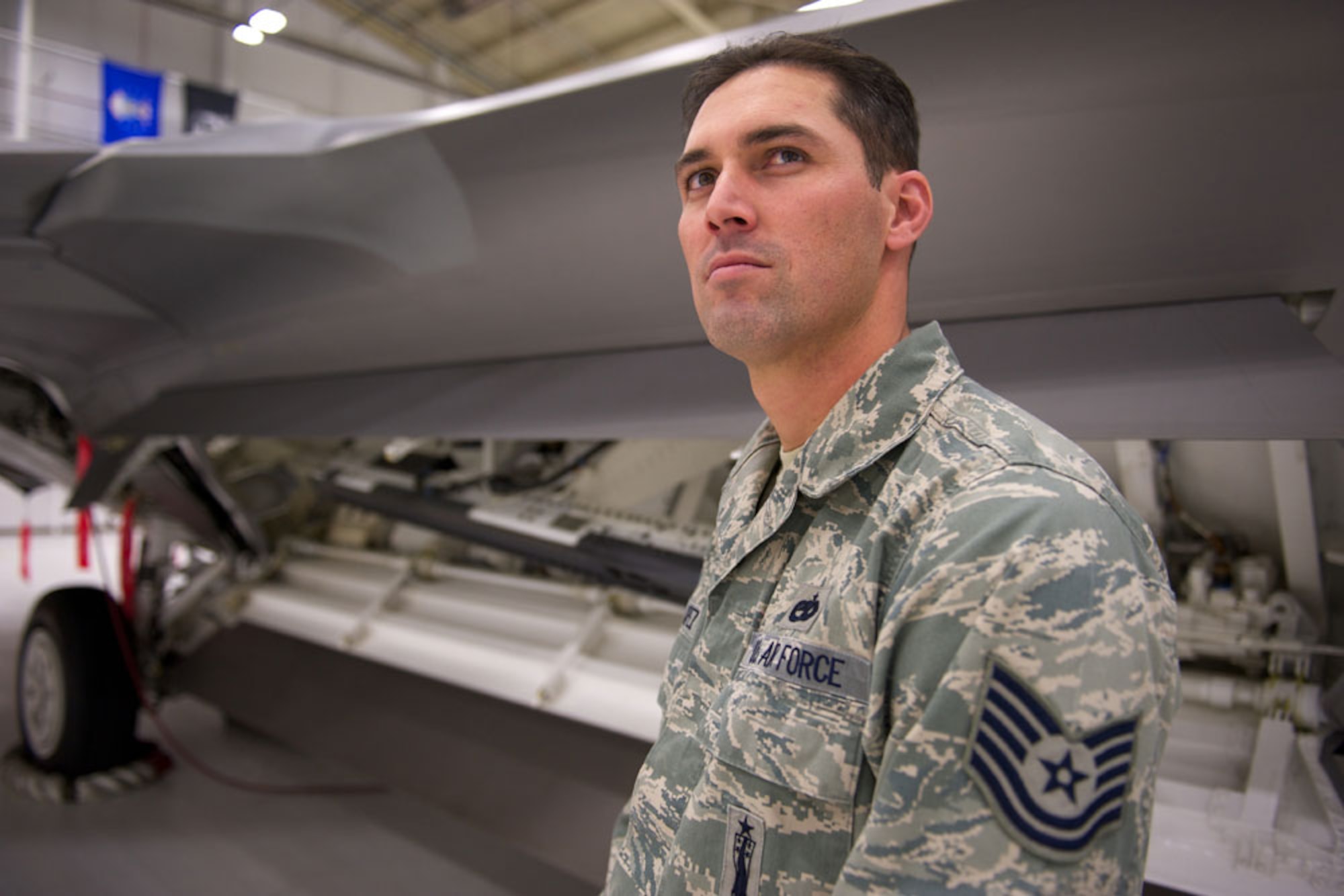 After receiving a check for $10,000, Tech. Sgt. Joshua Lopez, 90th Aircraft Maintenance Unit, stands by an F-22 Raptor with its configurable rail launcher exposed, Sept. 30, at the 90th Fighter Squadron hangar. Lopez identified a problem and provided a solution with the launcher, which netted him the cash reward through the Air Force’s Innovative Development through Employee Awareness program. (U.S. Air Force photo/David Bedard)