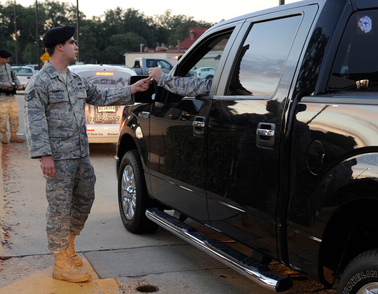 Staff Sgt. Garrett Thompson, 2nd Security Forces Squadron police services NCO, hands an Airman's identification card back to him Oct. 6 at the North gate on Barksdale Air Force Base, La. Thompson is a recent recipient of the major command-level Government Employees Insurance Company Military Service Award for 2011 and is a nominee for the Air Force-level GEICO award. (U.S. Air Force photo/Airman 1st Class Andrea F. Liechti)(RELEASED)