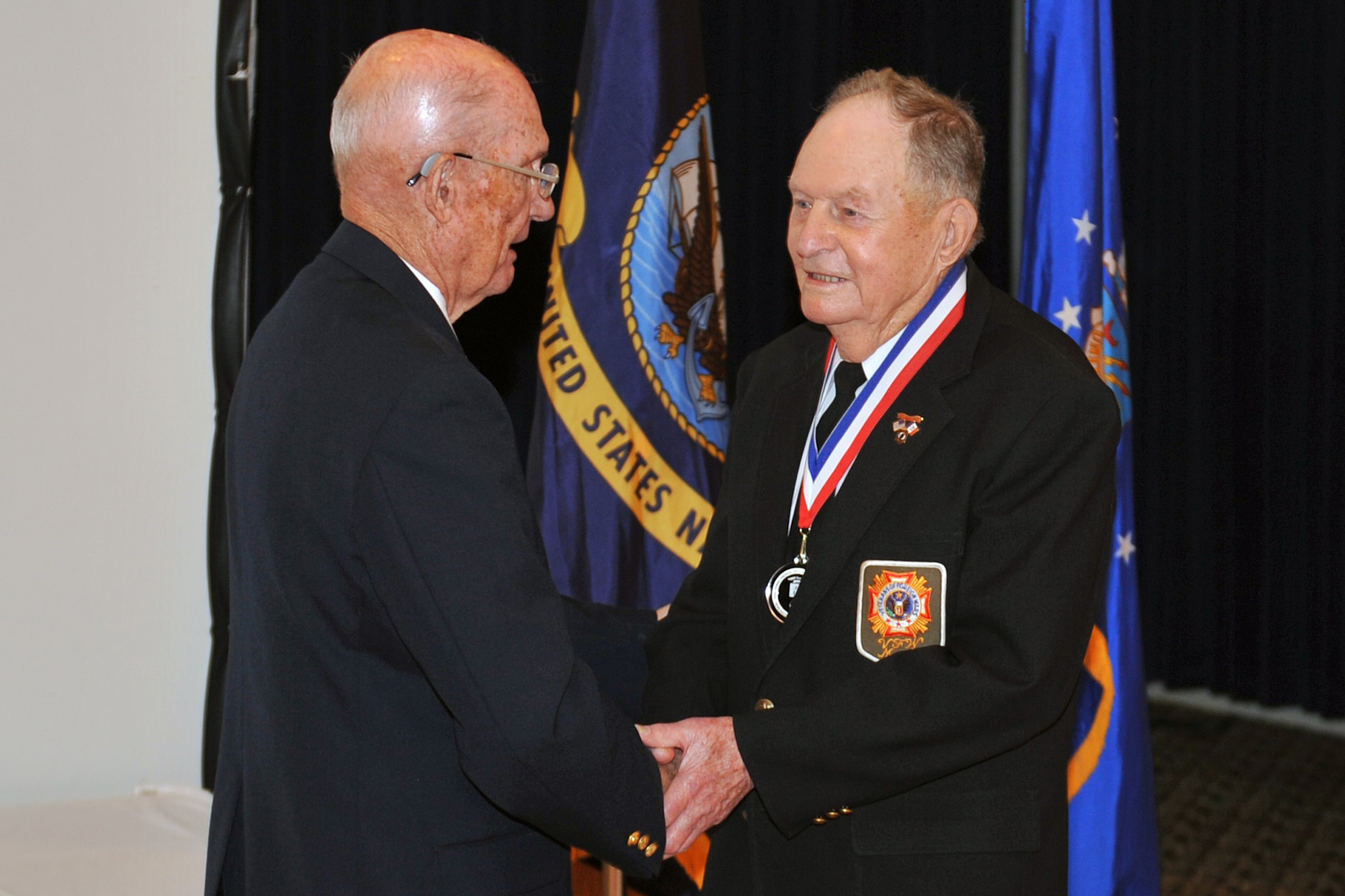 Retired Chief Master Sgt. of the Air Force James M. McCoy presents a medallion to retired U.S. Army Sgt. 1st Class Bill Roth, during a prisoner-of-war / missing-in-action remembrance luncheon at the Patriot Club on Offutt Air Force Base, Neb., Sept. 23.  Roth was one of nine former POW's who were honored during the remembrance luncheon for the sacrifices they made for their country. (U.S. Air Force photo by Jeff W. Gates/Released)