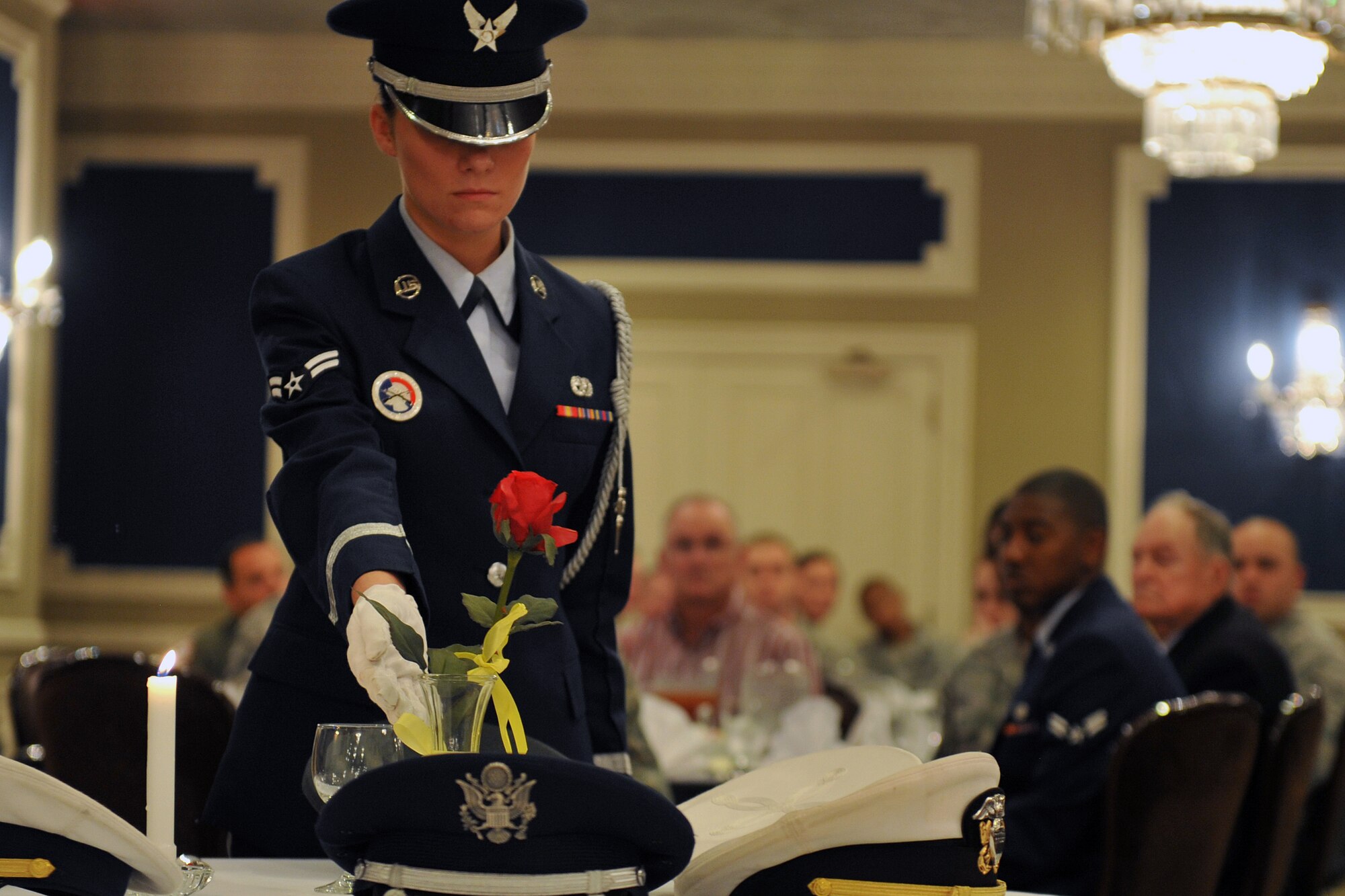 U.S. Air Force Airman 1st Class Naomi Hutchinson, Offutt honor guard, places a lone rose at the prisoner-of-war / missing-in-action table at a POW/MIA remembrance luncheon at the Patriot Club, Offutt Air Force Base, Neb., Sept. 23. The rose is to remind patrons of the life of each of the missing and their loved ones and friends who keep the faith. The vase is tied with a yellow ribbon to symbolize continued determination to account for missing members. (U.S. Air Force photo by Jeff W. Gates/Released)