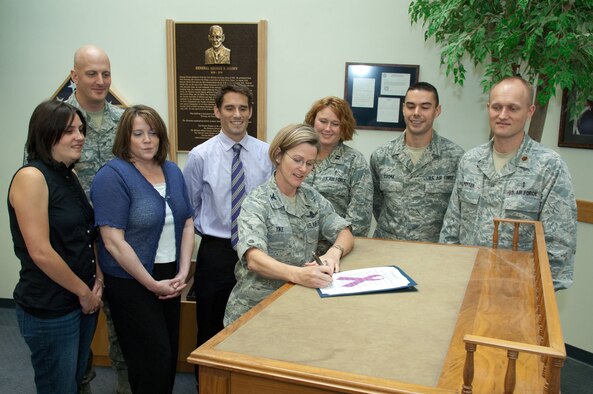 HANSCOM AIR FORCE BASE, Mass. – Col. Stacy L. Yike, 66th Air Base Group commander, signs a proclamation Sept. 30 declaring October as Domestic Violence Prevention and Awareness Month on Hanscom, as members of the Mental Health Flight, Family Advocacy Program and Chief Master Sergeant Baird Stiefel (back right), 66th Air Base Group superintendant, gather around. Look for activities and events around the base throughout the month promoting domestic violence prevention and awareness. (U.S. Air Force photo by Rick Berry)