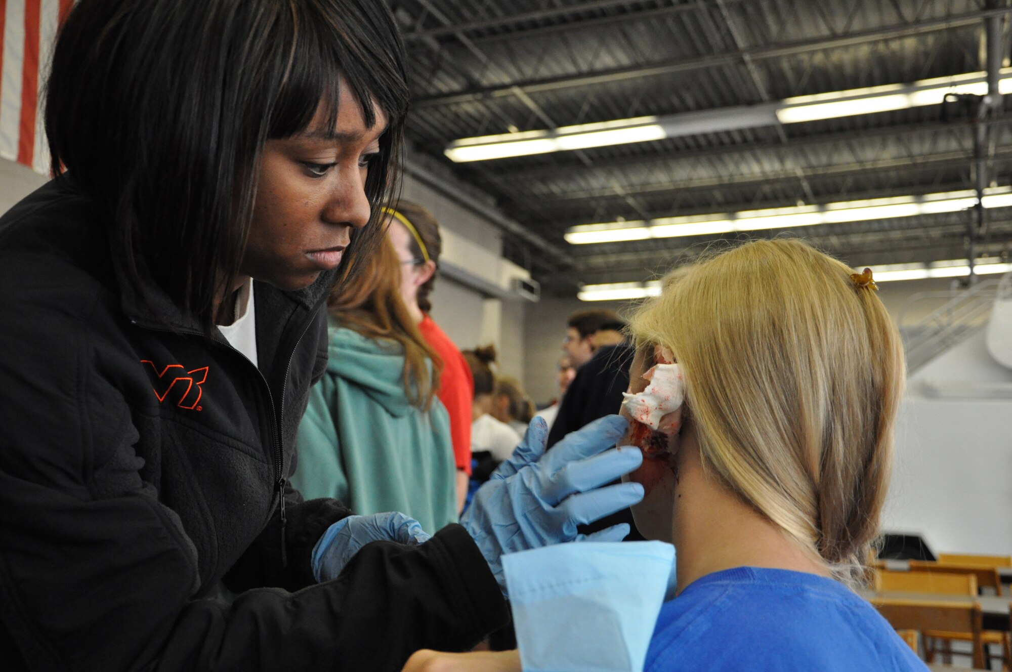 Staff Sgt. Monica Fray, 633rd Medical Group medic, applies moulage to a Denbigh High School student during the Newport News-Williamsburg International Airport’s disaster response mass casualty exercise Oct. 5. Local emergency responders treated the “victims” later in the day during the response portion of the exercise. (U.S. Air Force photo by Senior Airman Jason J. Brown/RELEASED)