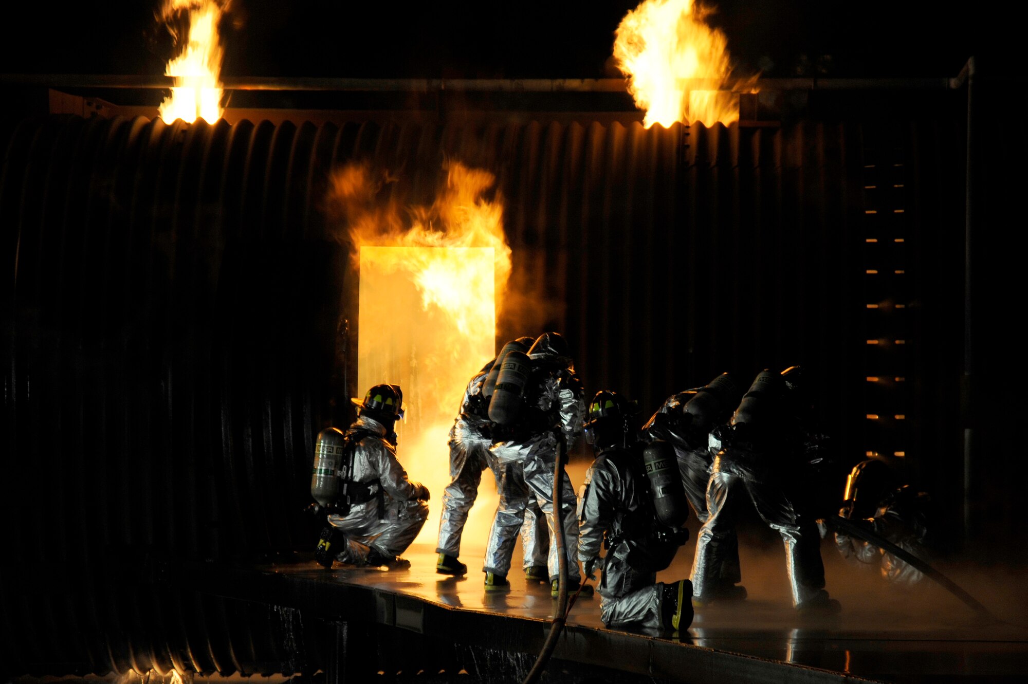 MISAWA AIR BASE, Japan - Firefighters from the 35th Civil Engineer Squadron along with distinguished visitors from Misawa Air Base prepares to enter a burning mock training aircraft at a nighttime demonstration during Fire Prevention Week here Oct. 5. The 35 CES fire department invited the Misawa community out for nighttime fire demonstrations to help promote Fire Prevention Week. This week the 35 CES has been educating the Misawa community on fire prevention in order to achieve their goal of zero mishaps. (U.S. Air Force photo/Tech. Sgt. Marie Brown)