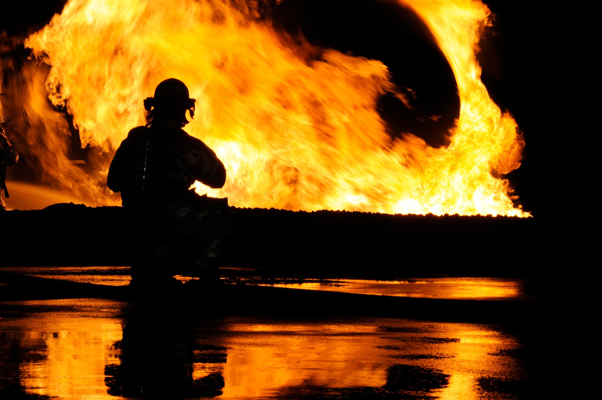 MISAWA AIR BASE, Japan - A firefighter from the 35th Civil Engineer Squadron stands by to assist with extinguishing a fire at a nighttime demonstration during Fire Prevention Week here Oct. 5. The 35 CES fire department invited the Misawa community out for nighttime fire demonstrations to help promote Fire Prevention Week. This week the 35 CES has been educating the Misawa community on fire prevention in order to achieve their goal of zero mishaps. (U.S. Air Force photo/Tech. Sgt. Marie Brown)