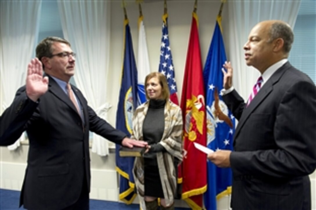 Jeh C. Johnson, right, Defense Departmenet general counsel, swears in Ashton B. Carter, left,  as the 31st Deputy Secretary of Defense, while Carter’s wife Stephanie, center holds the Bible, in a ceremony in the Pentagon, Oct. 6, 2011.  Carter was formerly the undersecretary of defense for Acquisition, Technology & Logistics. 