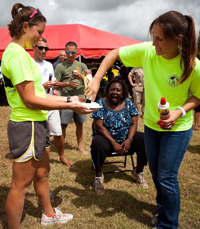 Casey S. Fleishmann (right), family readiness officer, Headquarters and Service Battalion, U.S. Marine Corps Forces, Pacific, and 1st Lt. Kerry Friedewald (left), adjutant, HqSvcBn, prepare a pie for the “pie in the face” fundraiser at the Bordelon Bash at Bordelon Field here Oct 7. The Bordelon Bash was a family fun day event hosted by the battalion.