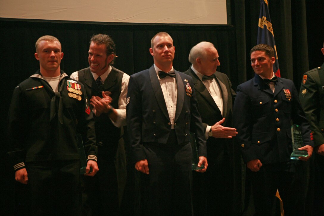 (left to right) Petty Officer 2nd Class, Ryan Wayne Tilley, corpsman, Headquarters Battalion, 2nd Marine Division, Staff Sgt. Benjamin G. Seekell, military working dog handler, Seymour Johnson Air Force Base, and Petty Officer 2nd Class, Thomas R. Taylor, damage controlman, Joint Maritime Training Center, all receive an award for their work deployed or stateside from the USO of North Carolina at the Raleigh Convention Center, Raleigh, N.C., Oct. 7. Hundreds of USO members and past and present servicemembers gathered to celebrate the 70th anniversary of the USO and to honor award recipients from all branches of the U.S military.