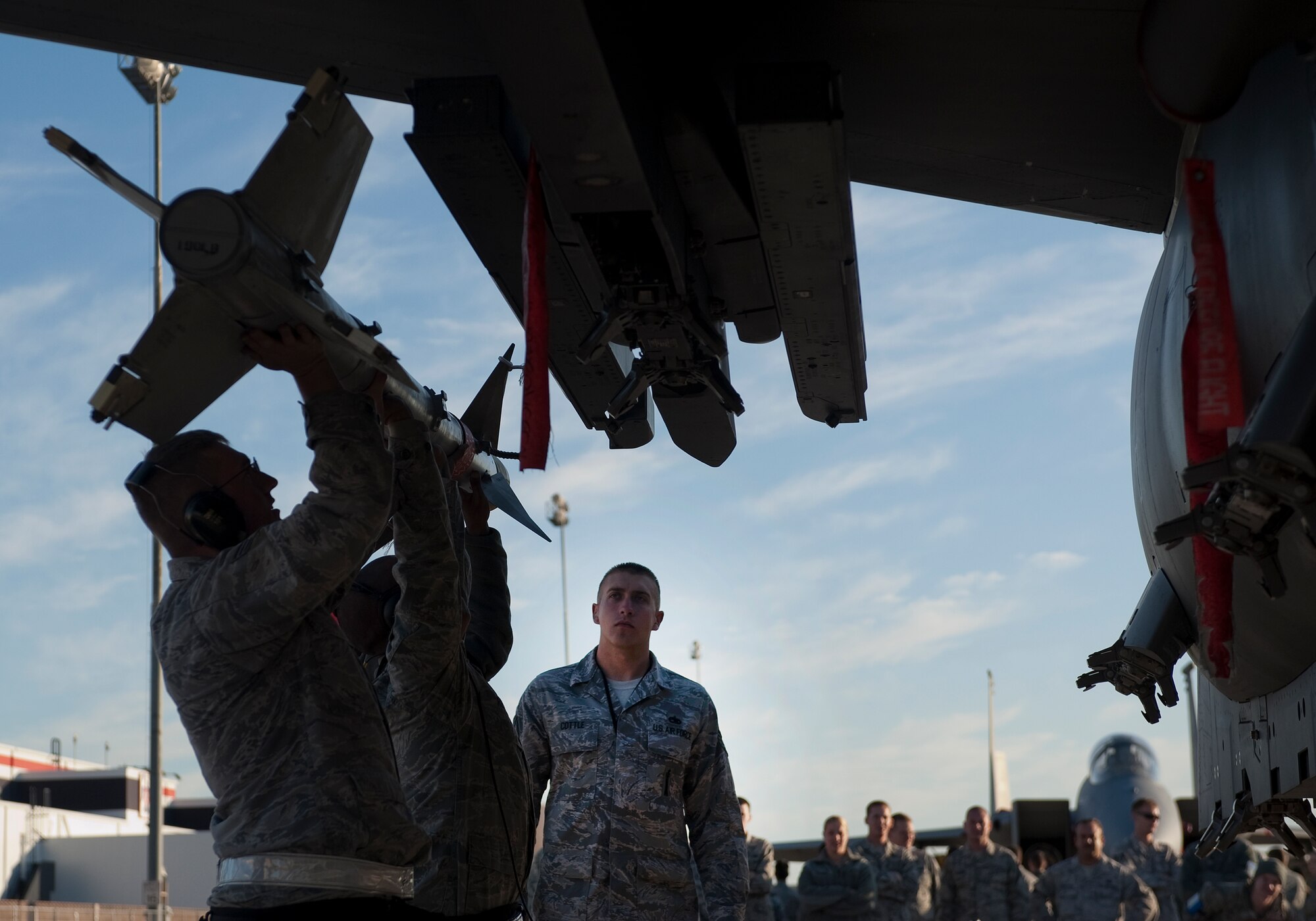 U.S. Air Force Staff Sgt. Justin Cottle. 757th Aircraft Maintenance Squadron aircraft armament systems craftsman, evaluates Airmen as they load AIM-9M Sidewinder on to an F-15 Eagle during the quarterly weapons load competition Oct. 7, 2011, at Nellis Air Force Base, Nev. Weapons load teams are evaluated for use of the checklist, safety, and overall speed. (U.S. Air Force photo by Staff Sgt. Christopher Hubenthal/Released)