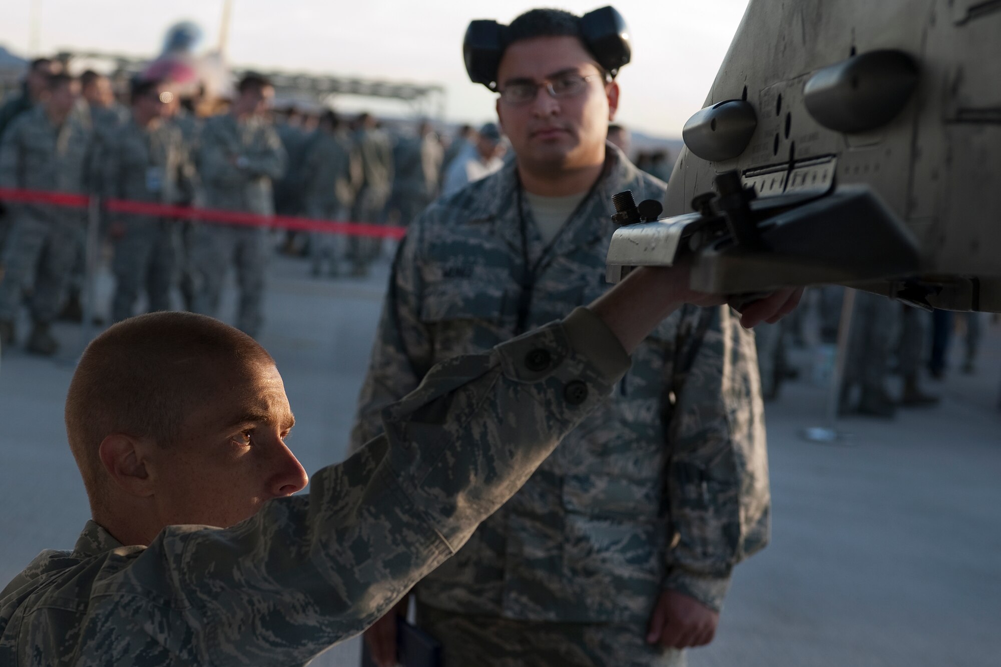 U.S. Air Force Senior Airman Robert Adams, 57th Aircraft Maintenance Squadron aircraft armament systems journeyman, prepares an F-16 Fighting Falcon to be armed as Staff Sgt. Hector Muniz,  57th Aircraft Maintenance Squadron aircraft armament systems craftsman, evaluates during the quarterly weapons load competition Oct. 7, 2011, at Nellis Air Force Base, Nev. Weapons load competitions are conducted quarterly to keep Airmen sharp and recognize superior performers. Weapons load teams are evaluated for use of the checklist, safety, and overall speed. (U.S. Air Force photo by Staff Sgt. Christopher Hubenthal/Released)
