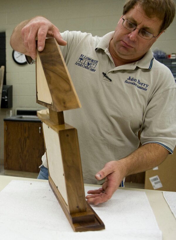 John Berry, 28th Force Support Squadron Arts and Crafts recreation assistant, looks over a completed retirement case in the Arts and Crafts Center on Ellsworth Air Force Base, S.D., Oct. 4, 2011. Retirement cases can be specially made or purchased from a selection of existing cases available at the Arts and Crafts Center. (U.S. Air Force photo by Airman 1st Class Kate Thornton/Released)
