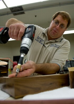 John Berry, 28th Force Support Squadron Arts and Crafts recreation assistant, inserts screws into the backing of a retirement case in the Arts and Crafts Center on Ellsworth Air Force Base, S.D., Oct. 4, 2011. This was the final step in the completing the two retirement shadow boxes. (U.S. Air Force photo by Airman 1st Class Kate Thornton/Released)