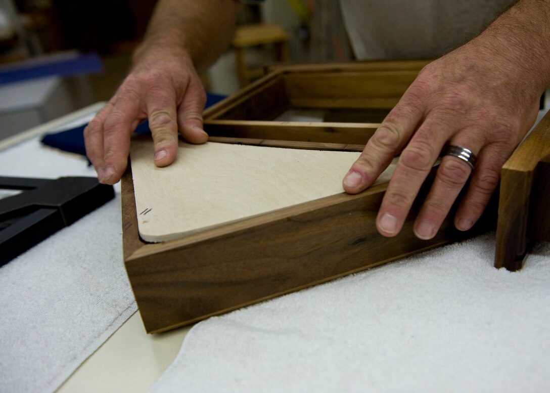 John Berry, 28th Force Support Squadron Arts and Crafts recreation assistant, inserts a wooden backing onto the top section of a retirement case in the Arts and Craft Center on Ellsworth Air Force Base, S.D., Oct. 4, 2011. The wooden backing completed the top section of the shadow. (U.S. Air Force photo by Airman 1st Class Kate Thornton/Released)
