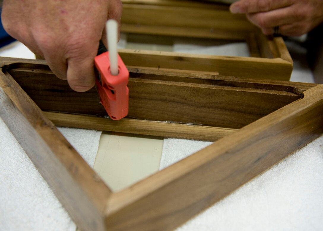 John Berry, 28th Force Support Squadron Arts and Crafts recreation assistant, applies hot glue to the top section of a retirement case in the Arts and Crafts Center on Ellsworth Air Force Base, S.D., Oct. 4, 2011. Berry is preparing the section that encases the folded American flag for a retirement shadow box. (U.S. Air Force photo by Airman 1st Class Kate Thornton/Released)