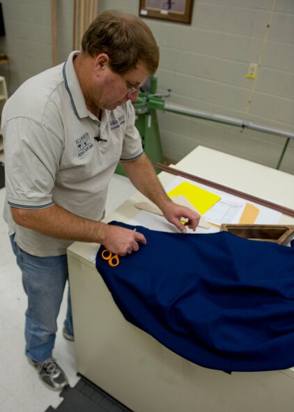 John Berry, 28th Force Support Squadron Arts and Crafts recreation assistant, sizes and cuts blue cloth for a background of a retirement case in the Arts and Crafts Center on Ellsworth Air Force Base, S.D., Oct. 4, 2011. Berry cuts the glass and assembles each retirement case by hand. (U.S. Air Force photo by Airman 1st Class Kate Thornton/Released)