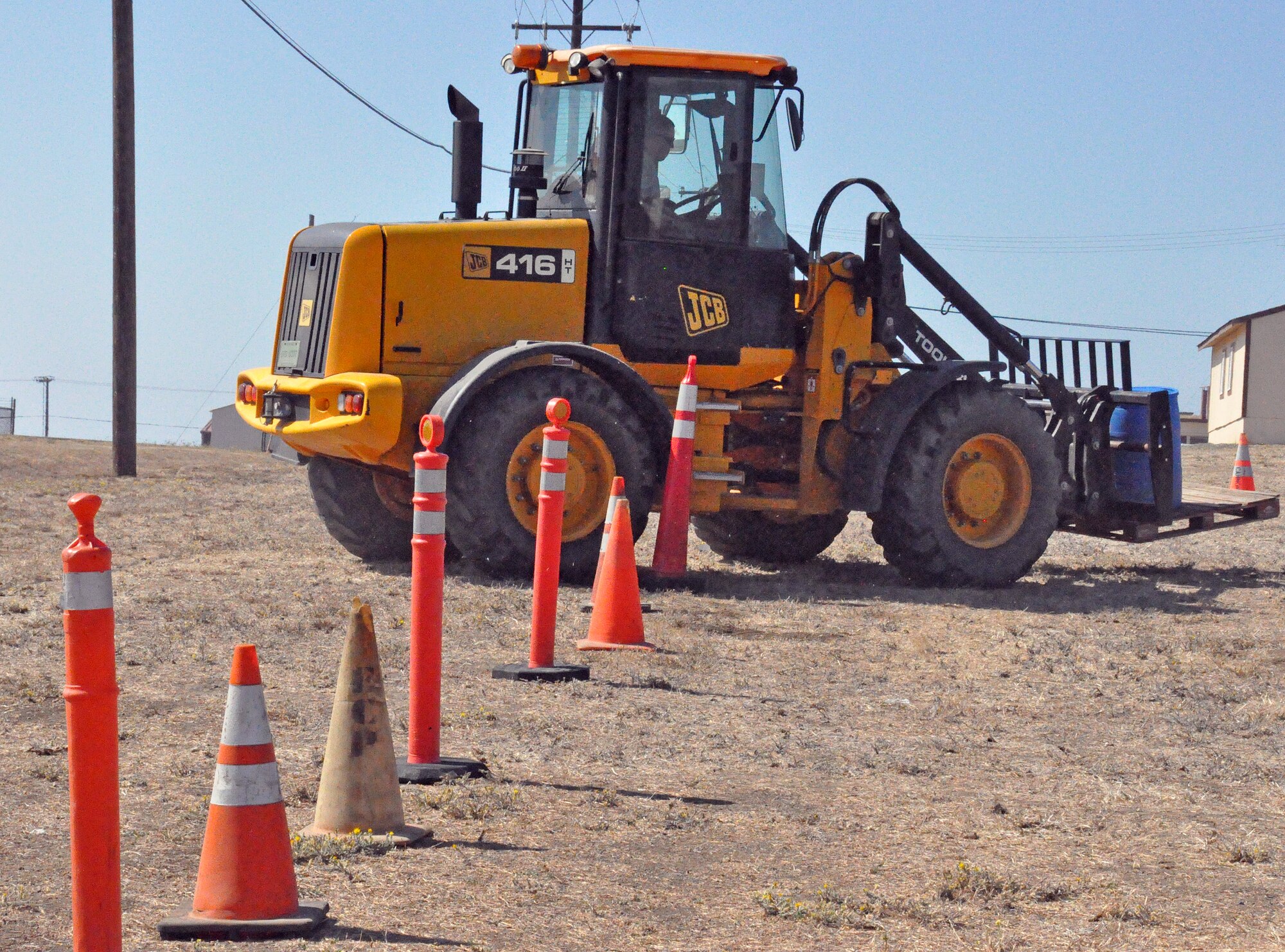 Once the dump truck has successfully reached the end of the trail, the driver of the loader must weave the vehicle in and out of a cone path all while carrying a barrel containing 50 gallons of water. (U.S. Air Force photo/ Airman Madelyn Ottem)