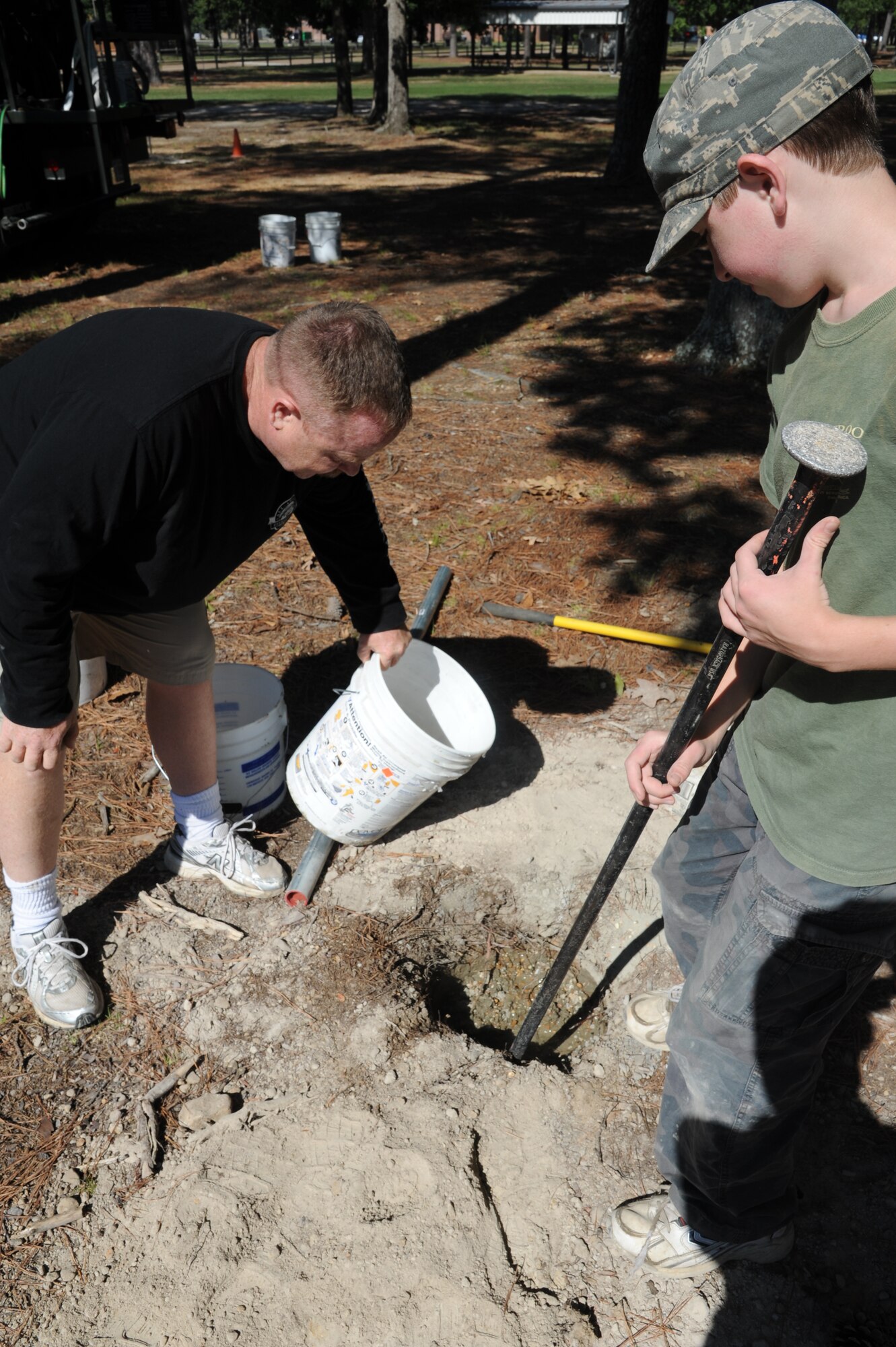 Glenn and Gordon Berquist, project volunteers, mix concrete to hold a pole on the disc golf course on Sept. 24. The course has 18 holes and is located across the street from the Fitness Center. (U.S. Air Force photo/Airman 1st Class Chase Hedrick)