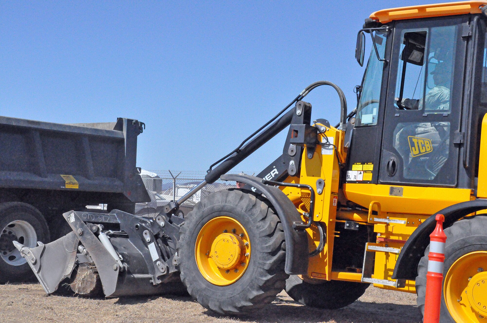 Senior Airman Core uses the modified front loader to pick up a log and place it in the dump truck as quickly and safely as possible to advance her flight in the timed competition. (U.S. Air Force photo/ Airman Madelyn Ottem)