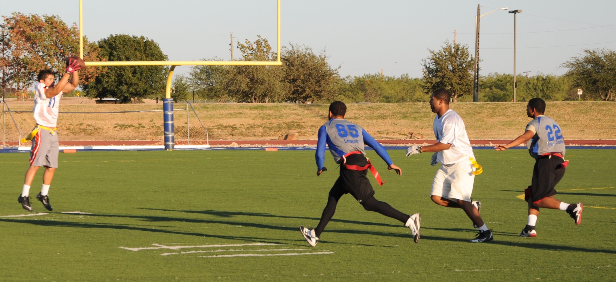 GOODFELLOW AIR FORCE BASE, Texas--  Junkyard Dawgs team member Anthony Castillo from the Force Support Squadron catches a lateral pass from Clifton Gathers, 17th Comptroller Squadron, as the opposing team, the 316th Training Squadron Sharks,  attempts to tackle him Oct. 6 at Mathis Field. The Junkyard Dawgs beat the Sharks 19:0, taking home the season’s championship. (U.S. Air Force photo/Airman 1st Class Jessica Keith)