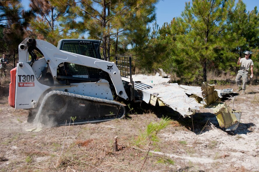 U.S. Air Force Airman 1st Class Tyler Eubank uses a multi-terrain loader to transport a piece of a crashed A-10C Thunderbolt II aircraft as he is guided by Senior Airman Todd Alter Oct. 4, 2011, in a non-residential area northeast of Berlin, Ga., in Cook County. Eubank and Alter are both heavy equipment operators with the 23rd Civil Engineer Squadron who were part of a team tasked to recover all remains of the crash site while preserving the natural habitat. (U.S. Air Force photo by Staff Sgt. Jamal D. Sutter/Released) 