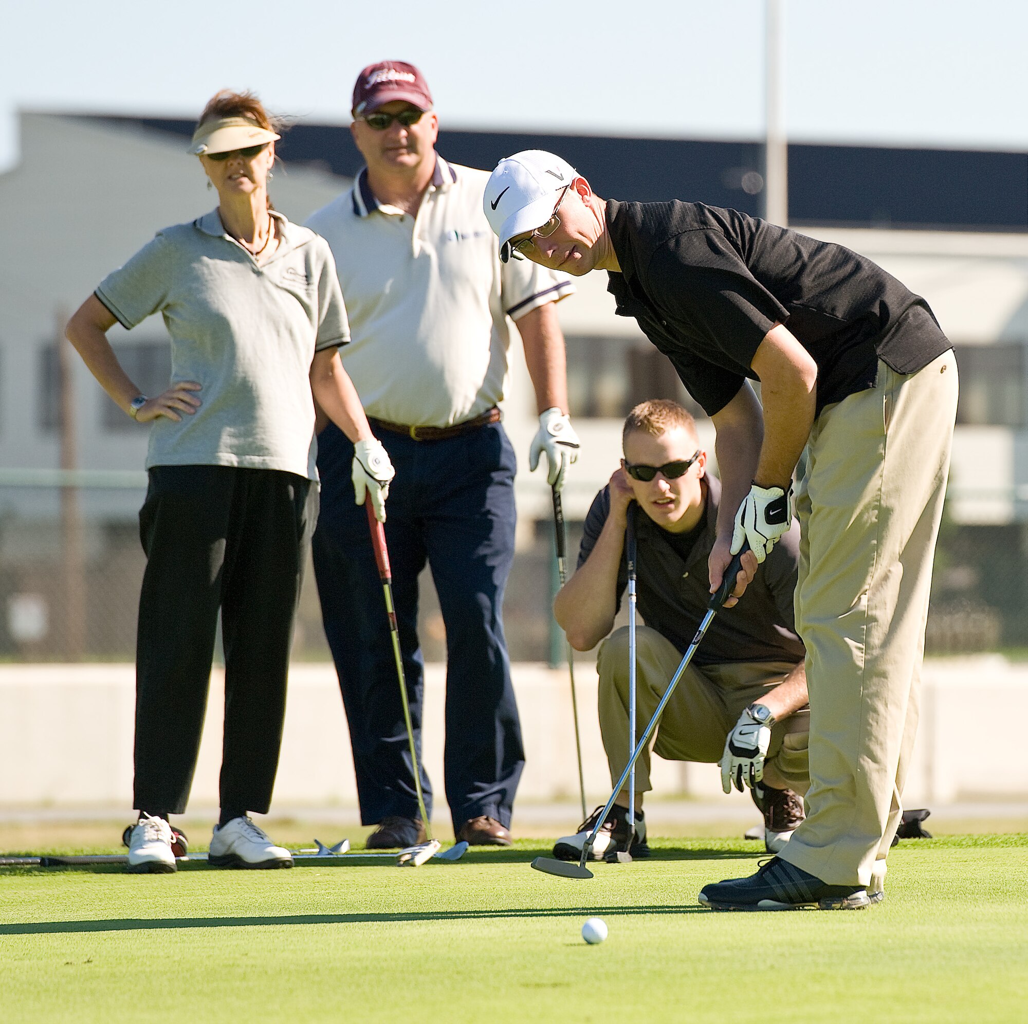 Bettie Campbell (left), Dave Clendaniel and Airman 1st Class Aaron Kind watch as Senior Airman Andrew Brande putts at the Bluesuiters’ Golf Tournament Oct. 5, 2011, at Dover Air Force Base, Del. The Bluesuiters’ Golf Tournament teams military members with local community members for a day of golf. Campbell and Clendaniel, both from the Dover Federal Credit Union, sponsored Kind and Brande for the tournament. (U.S. Air Force photo by Roland Balik)