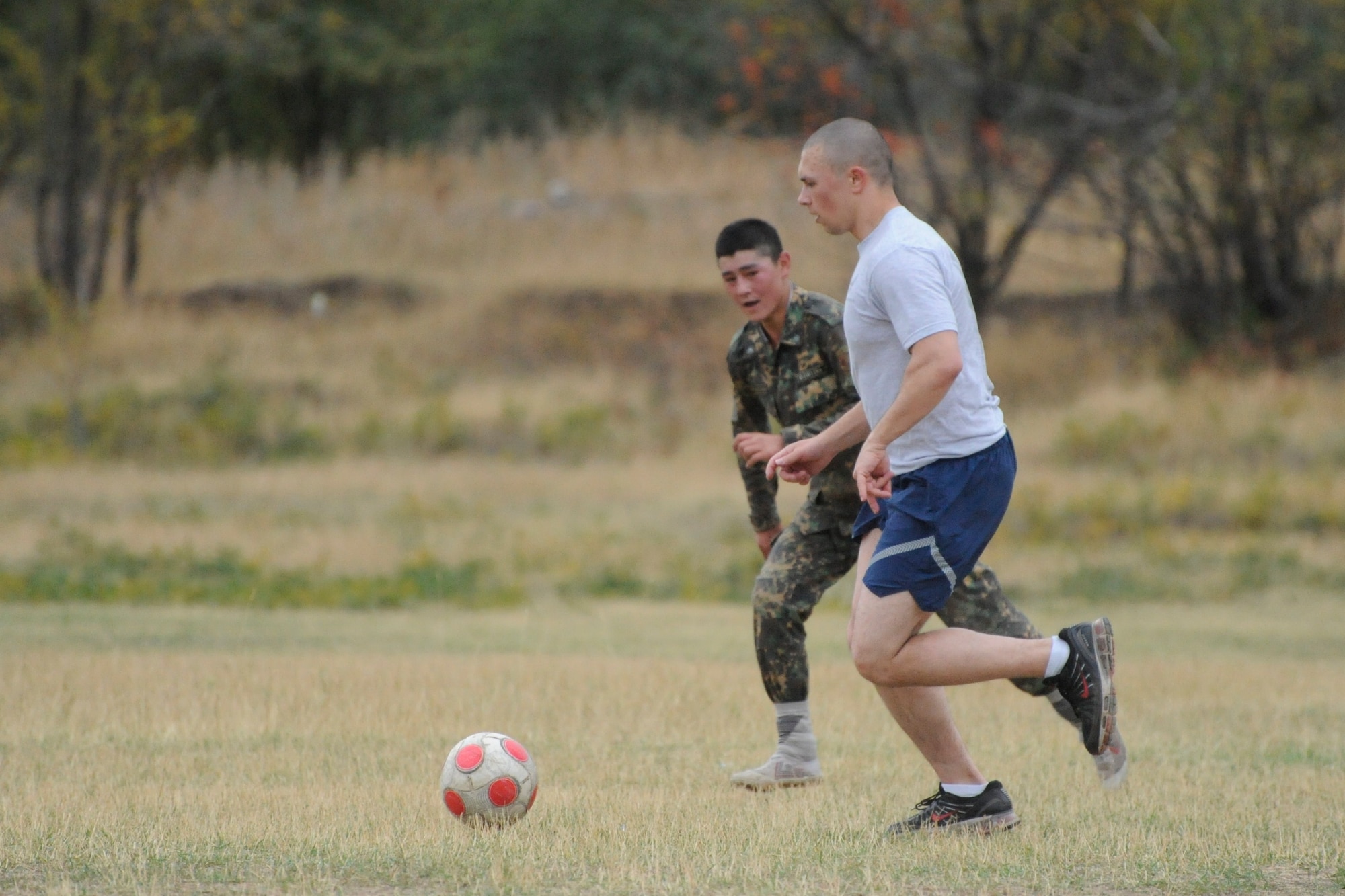 Senior Airman Michael Abrash races for the ball during a soccer game with Kyrgyz Republic soldiers at the Koi Tash Noncommissioned Officers Academy, Kyrgyzstan, after participating in a language lab Oct. 6. Abrash is a Theater Security Cooperation linguist. He is deployed to the Transit Center at Manas from March Air Reserve Base, Calif. (U.S. Air Force photo/Tech. Sgt. Tammie Moore)