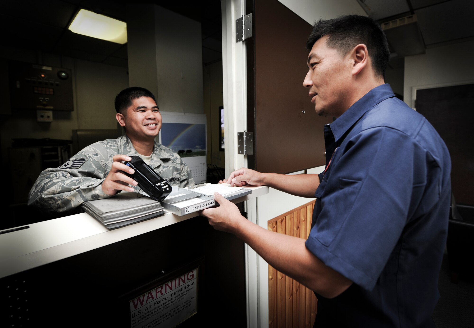 YOKOTA AIR BASE, Japan -- Staff Sgt. Jeffrey Legaspi, 374th Logistics Readiness Squadron fuels service center controller, issues a clipboard, checklist and an automated point of sale device to Akira Tanaka, 374th LRS fuels distribution operator, at Yokota Air Base, Japan, Sept. 28, 2011. These items help operators to safely and accurately provide jet fuel to aircraft at Yokota. (U.S. Air Force photo/Staff Sgt Stacy Moless)