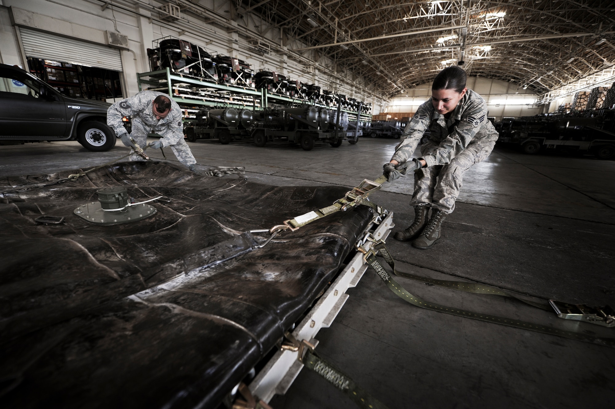 YOKOTA AIR BASE, Japan --Technical Sgt. Keith Sutton and Senior Airman Sarah Bishop, 374th Logistics Readiness Squadron fuels mobility support, palletizes a 3,000-gallon bladder for an aerial bulk fuel delivery system kit, at Yokota Air Base, Japan, Sept. 28, 2011. Sutton and Bishop took the bladder off to conduct an annual required inspection, then strapped it back onto the pallet for transport. (U.S. Photo/Staff Sgt Stacy Moless)