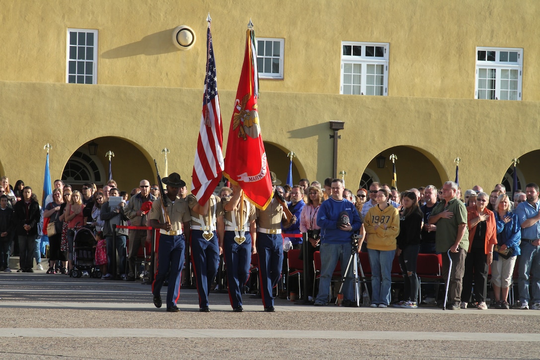 A Marine color guard marches the colors out between a crowd of families during the Morning Colors Ceremony Oct. 7. While the colors were marched out the national anthem was played. The attendees of the ceremony removed any hats that they were wearing and placed their right hand over their heart while the anthem played.::r::::n::::r::::n::::r::::n::