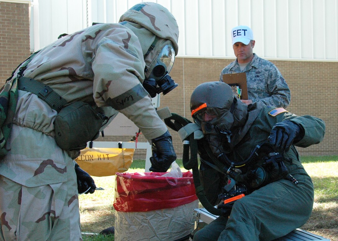 Tech. Sgt. Kenneth Petty of the 919th Operations Support Squadron, left, instructs Lt. Col. Chris Snider from the 711th Special Operations Squadron on the safe removal of his protective ensemble on the contamination control line after a recent chemical warfare defense scenario at Duke Field, Fla. Behind them, Tech. Sgt. Christiaan Becker, an exercise evaluation team member, observes.  The simulation was one of several conducted during the 919th Special Operations Wing's Operational Readiness Exercise, which tested the reservists' ability to survive and operate after an enemy attack.  (U.S. Air Force photo/Dan Neely)