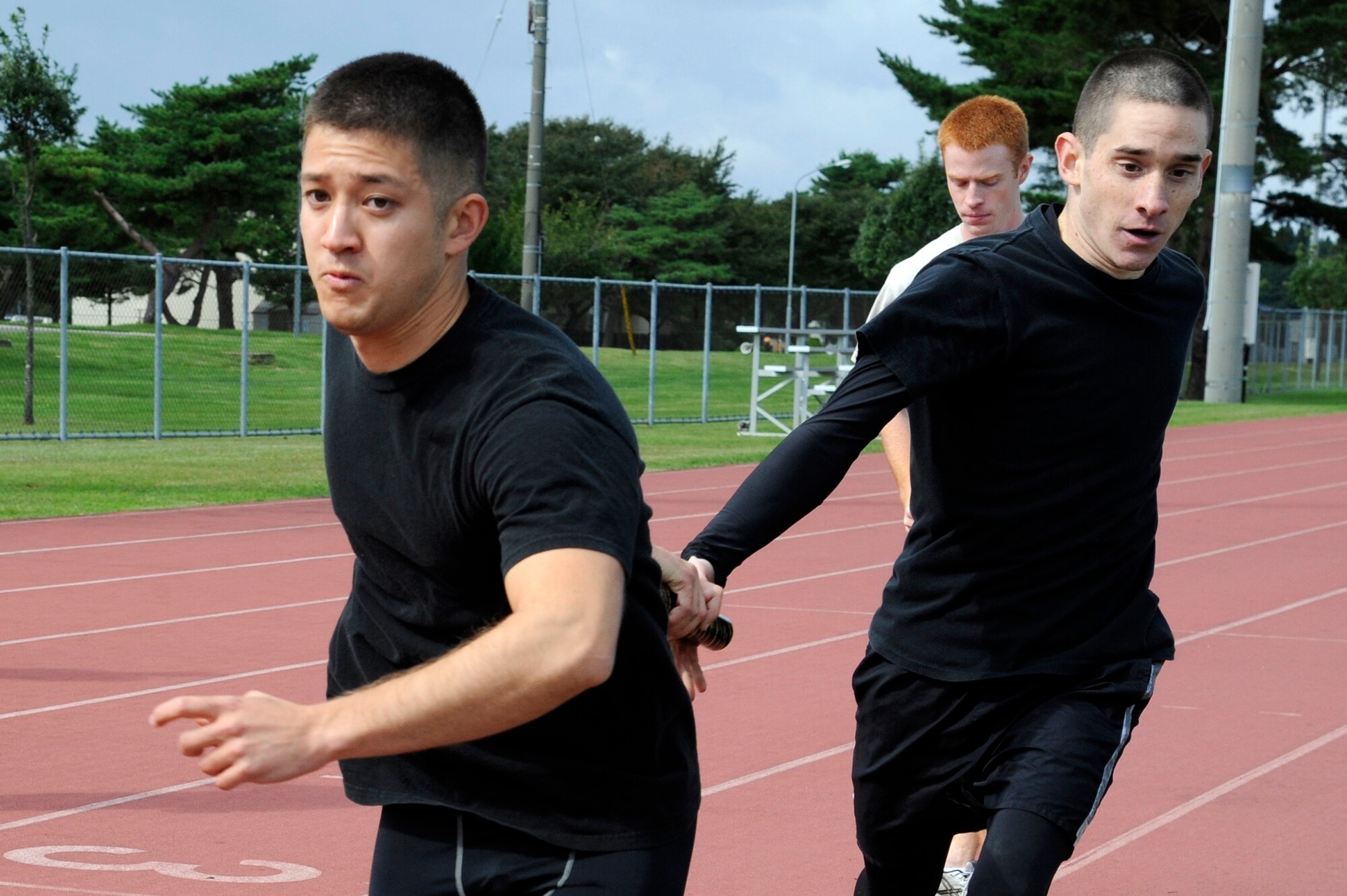 MISAWA AIR BASE, Japan - George Noah, left, takes the baton from Richard Neal, both from the 35th Maintenance Squadron, in the 4x400 relay race during the wing sports day here Oct. 7. The 35th Fighter Wing held a sports day to promote physical fitness, teamwork, competition, sportsmanship and esprit de corps. The day was kicked off with a 3-mile run followed by various sporting events to include relay races, basketball, softball, ultimate frisbee, soccer and a readiness competition. Approximately 14 units from the base formed teams to participate in each event. (U.S. Air Force photo/Tech. Sgt. Marie Brown)
