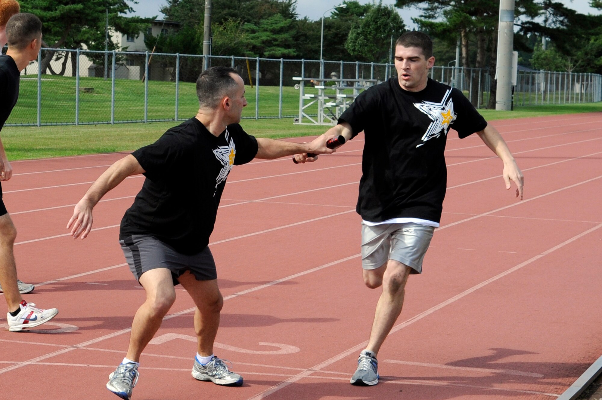 MISAWA AIR BASE, Japan - Joshua Evans, left, takes the baton from Matthew Overton, both from the 35th Communications Squadron, in the 4x400 relay race during the wing sports day here Oct. 7. The 35th Fighter Wing held a sports day to promote physical fitness, teamwork, competition, sportsmanship and esprit de corps. The day was kicked off with a 3-mile run followed by various sporting events to include relay races, basketball, softball, ultimate frisbee, soccer and a readiness competition. Approximately 14 units from the base formed teams to participate in each event. (U.S. Air Force photo/Tech. Sgt. Marie Brown)