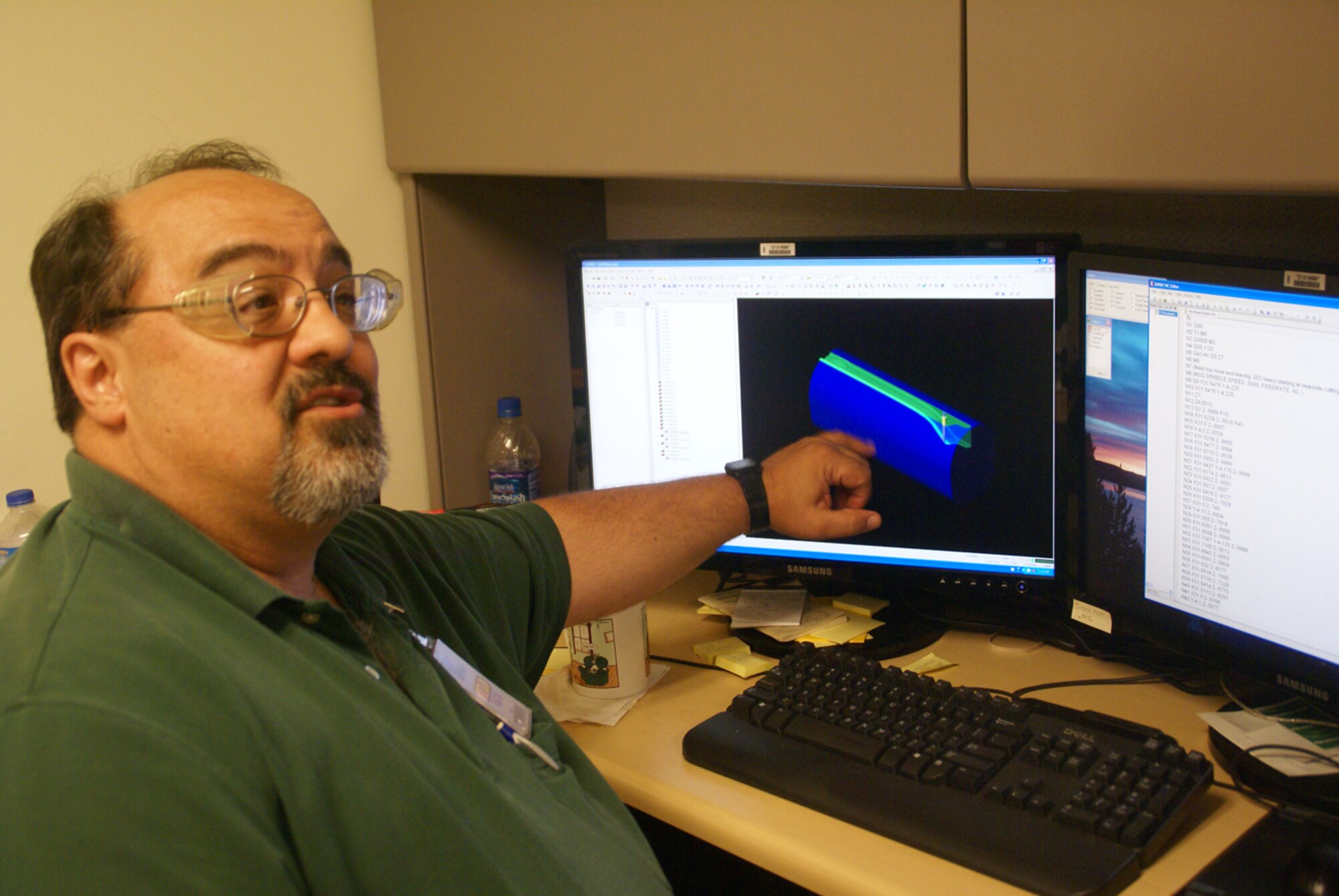 Joel Gregory, an ATA numerical control programmer in AEDC’s Model Shop, explains how he programs more than a dozen different machines to cut chunks of metal into parts that made up the B-52 model used in store separation testing at AEDC. (Photo by Philip Lorenz III)