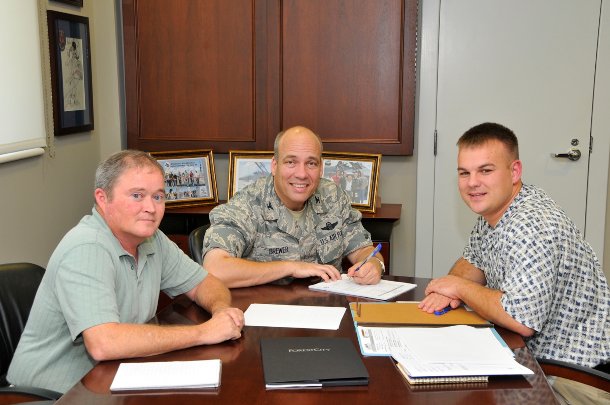 From left to right, Arnold AFB Housing Manager Mark Anderson, looks on as AEDC Commander Col. Michael Brewer signs his housing lease, with Parry Hazen, Arnold AFB community manager for Forest City Enterprises, on hand to explain the lease documents. The signing coincides with the recent finalization of base housing’s privatization with Forest City Military Communities LLC as the official leaser. (Photo by Rick Goodfriend)