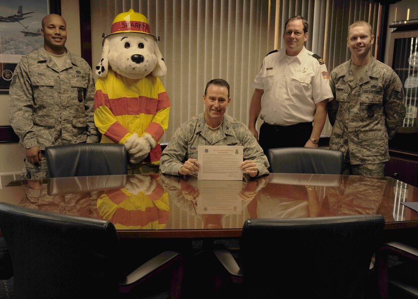 Col. Tim Bush, 319th Air Base Wing commander, holds the Fire Prevention Week Proclamation on Oct. 11 at Grand Forks Air Force Base, N.D.  Col. Bush – accompanied by (from the left) Tech. Sgt. Byron Ball, 319th Civil Engineering Squadron fire inspector, Sparky the Fire Dog, Ron Bergh, 319th CES fire chief and Tech. Sgt. Jeffery Rueben, 319th CES assistant chief of fire prevention -- signed the proclamation supporting the commitment to the safety and security of all those living, working and visiting the base.  This year’s theme is “Protect Your Family from Fire” to help lower the annual average of approximately 3,000 lost lives due to fire incidents. (U.S. Air Force photo by Airman 1st Class Ashley N. Taylor)