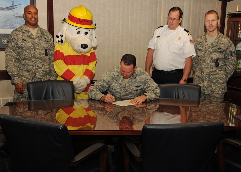 Col. Tim Bush, 319th Air Base Wing commander, signs the Fire Prevention Week Proclamation on Oct. 11 at Grand Forks Air Force Base, N.D.  Col. Bush – accompanied (from the left) by Tech. Sgt. Byron Ball, 319th Civil Engineering Squadron fire inspector, Sparky the Fire Dog, Ron Bergh, 319th CES fire chief and Tech. Sgt. Jeffery Rueben, 319th CES assistant chief of fire prevention - signed the proclamation supporting the commitment to the safety and security of all those living, working and visiting the base.  This year’s theme is “Protect Your Family from Fire” to help lower the annual average of approximately 3,000 lost lives due to fire incidents. (U.S. Air Force photo by Airman 1st Class Ashley N. Taylor)