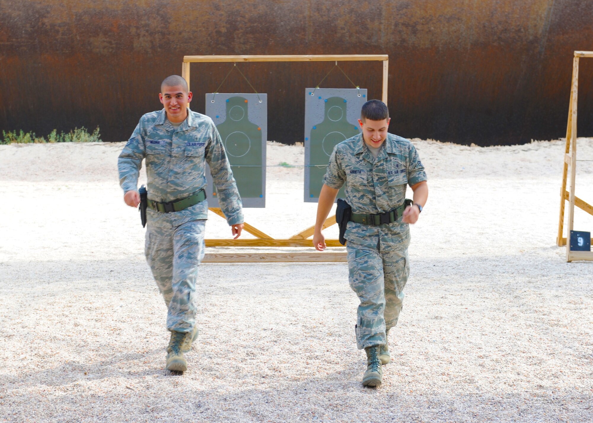 Staff Sgt. Juan Medina, and Senior Airman Alexander Arrieta, 7th Medical Operations Squadron, walk back to the firing line after moving their target back, Oct. 5, 2011, at Dyess Air Force Base, Texas. Airmen must go through M-9 qualification before they can deploy. (U.S. Air Force photo by Airman 1st Class Cierra Bullock/Released)
