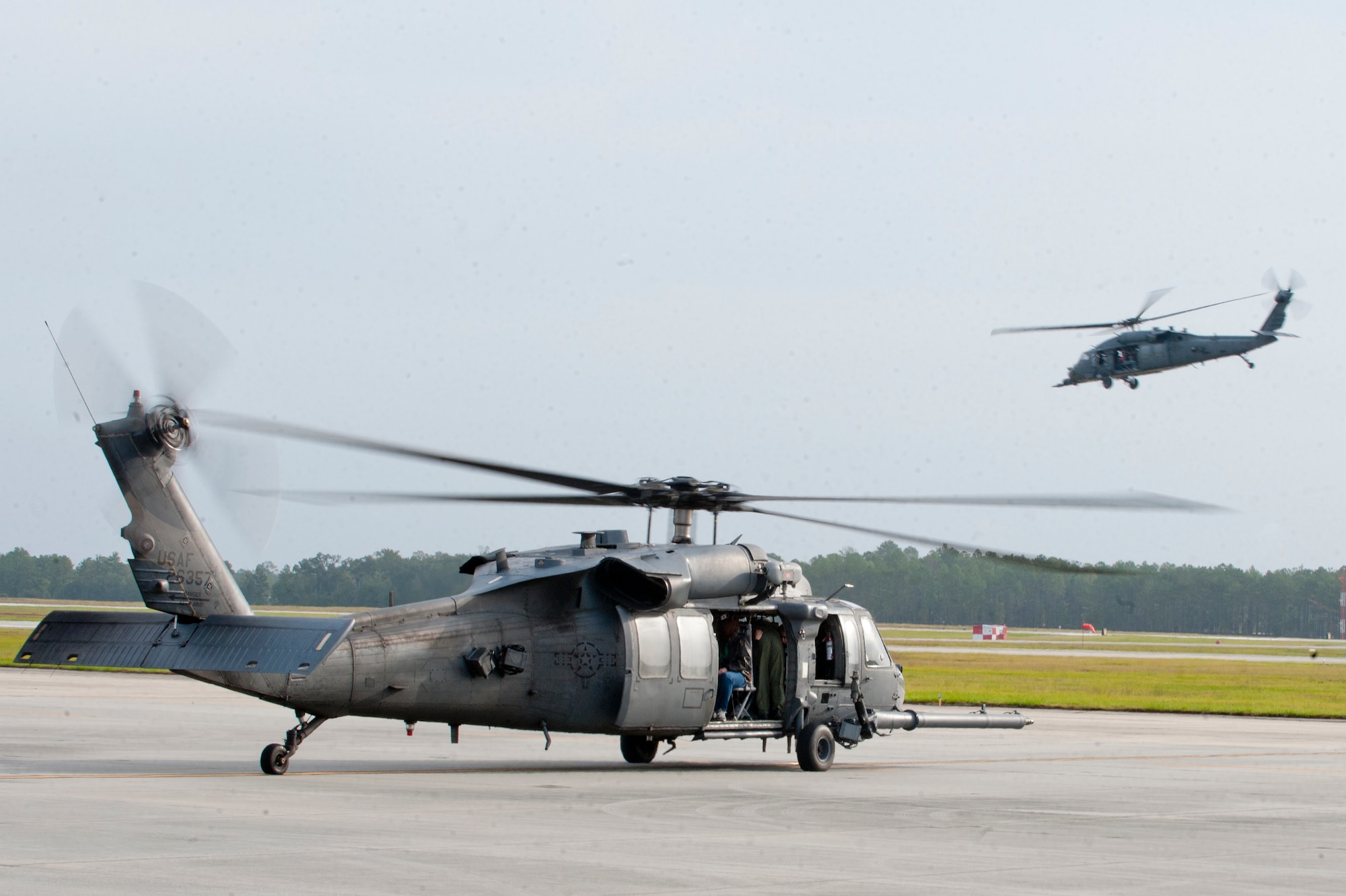 An HH-60G Pave Hawk from the 41st Rescue Squadron prepares to taxi out as another Pave Hawk flies by during Spouse Orientation Day Oct. 8, 2011, at Moody Air Force Base, Ga. The Pave Hawks provided incentive flights to the spouses of squadron members. (U.S. Air Force photo by Staff Sgt. Joshua J. Garcia/Released) 