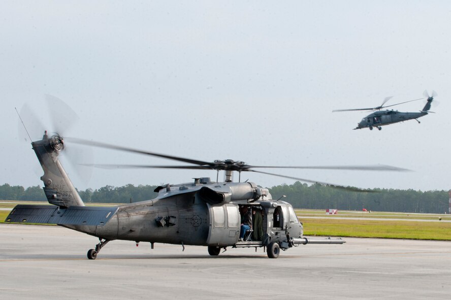 An HH-60G Pave Hawk from the 41st Rescue Squadron prepares to taxi out as another Pave Hawk flies by during Spouse Orientation Day Oct. 8, 2011, at Moody Air Force Base, Ga. The Pave Hawks provided incentive flights to the spouses of squadron members. (U.S. Air Force photo by Staff Sgt. Joshua J. Garcia/Released) 