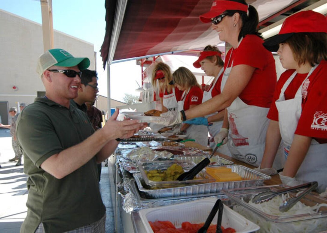 A member of a local community cooking team serves food to family member attending the 147th Reconnaissance Wing Family Day at Ellington Field Joint Reserve Base, Houston, 1 October 2011.   Family Day is held once a year to recognize and honor our family members.