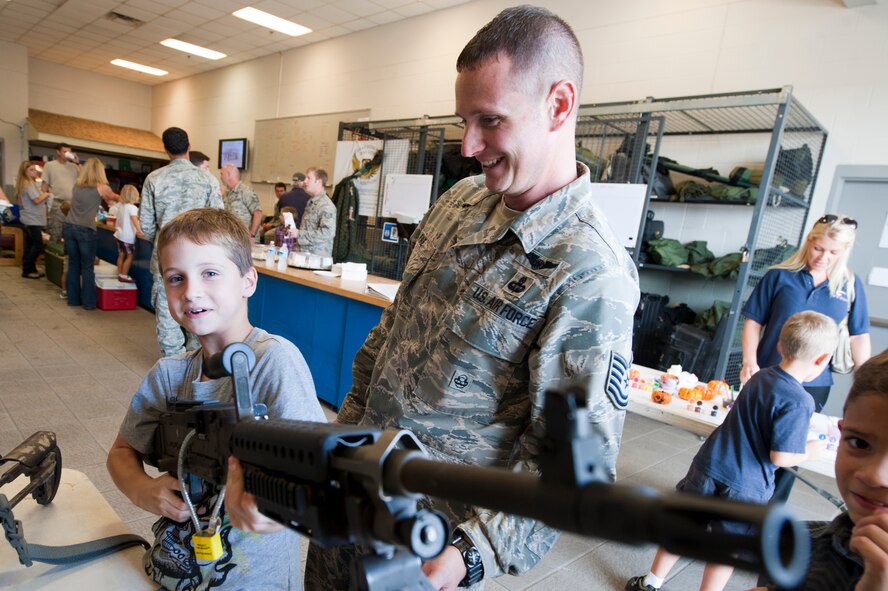 U.S. Air Force Tech. Sgt. Jason Fike, 38th Rescue Squadron, watches as his son Triston handles an M240 Bravo machine gun, during Spouse Orientation Day at Moody Air Force Base, Ga., Oct. 7, 2011. Throughout the day, the 38th RQS provided many attractions to educate family members about the jobs of their military spouse and parent. (U.S. Air Force photo by Staff Sgt. Joshua J. Garcia/Released) 