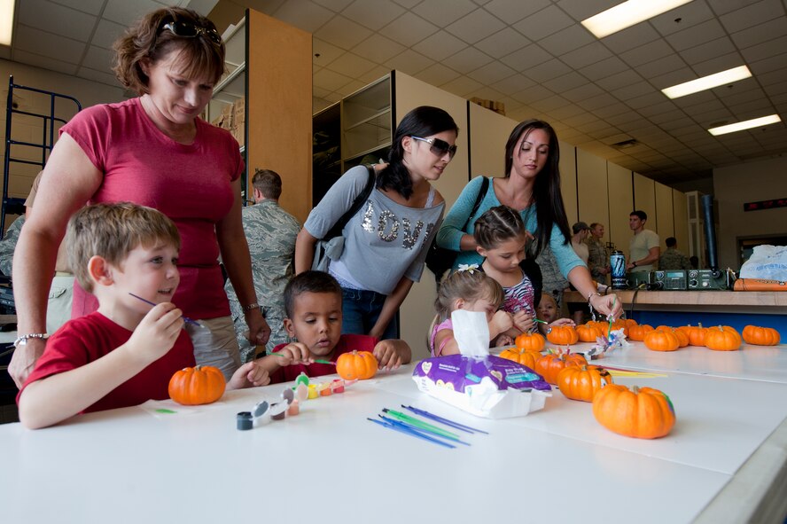 Spouses and their kids of the 38th Rescue Squadron paint pumpkins at the arts and crafts table during Spouse Orientation Day  at Moody Air Force Base, Ga., Oct. 7, 2011. The 38th RQS provided an assortment of activities for family members to partake in, ranging from wall climbing to a tour of a HH-60G Pave Hawk aircraft. (U.S. Air Force photo by Staff Sgt. Joshua J. Garcia/Released)